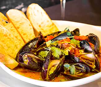 Steamed mussels in a rich tomato-based broth, garnished with fresh herbs and served with toasted bread slices at Wyoming Ale Works.