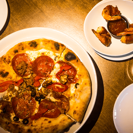 Wood-fired pepperoni pizza with sausage and olives served alongside crispy shrimp with dipping sauce at Wyoming Ale Works.